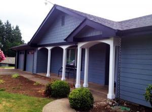 A freshly painted exterior house, featuring gray siding, black trim, and white columns as accent pieces. 