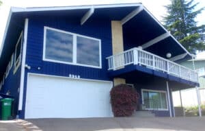 Exterior of a house painted by Sound Painting Solutions with rich blue siding and white trim and garage door