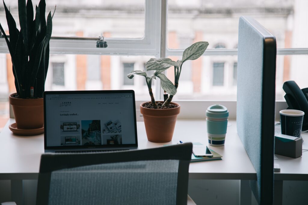 A laptop on a desk overlooking a window