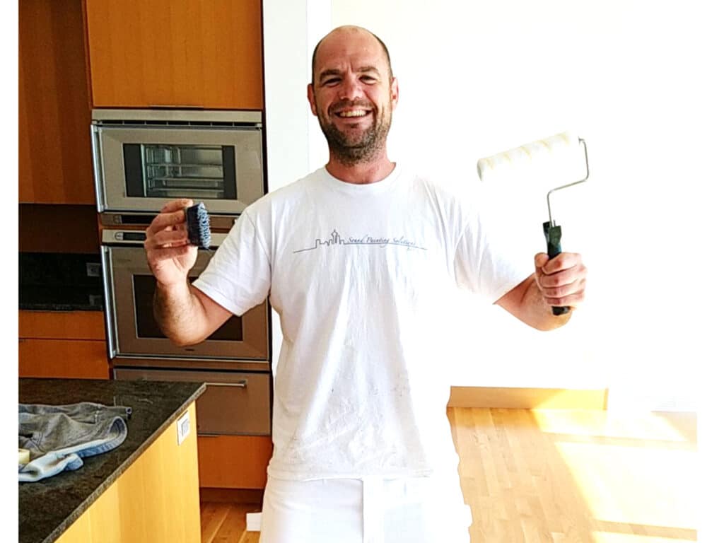 Painter Kevin smiling and holding a scrub brush and roller