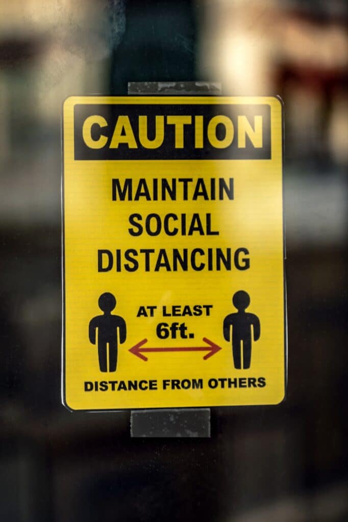A sign that says "Caution - Maintain Social Distancing - At least 6 ft. distance from others